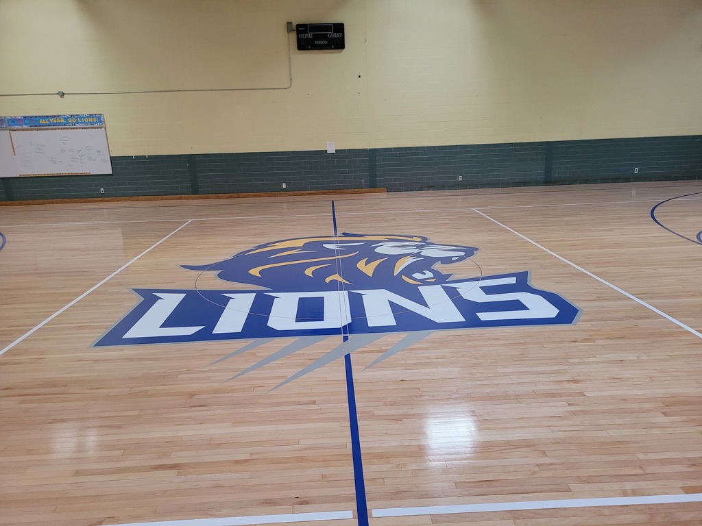 Gym floor with blue, white, and gold lion head and lettering that says Lions